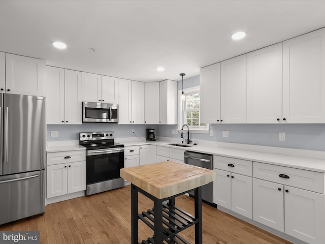 kitchen with sink, white cabinets, hanging light fixtures, and appliances with stainless steel finishes