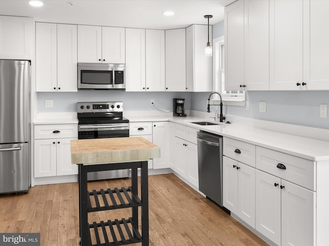 kitchen with appliances with stainless steel finishes, pendant lighting, white cabinetry, and sink