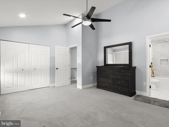 bedroom featuring ceiling fan, high vaulted ceiling, light carpet, and ensuite bath