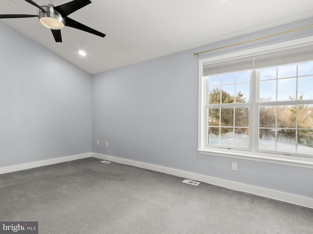 carpeted spare room with ceiling fan, vaulted ceiling, and a healthy amount of sunlight