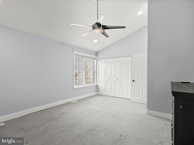 unfurnished bedroom featuring ceiling fan, light colored carpet, a closet, and lofted ceiling