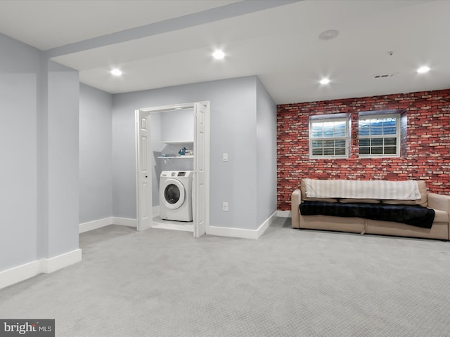 clothes washing area with brick wall, washer / clothes dryer, and light colored carpet