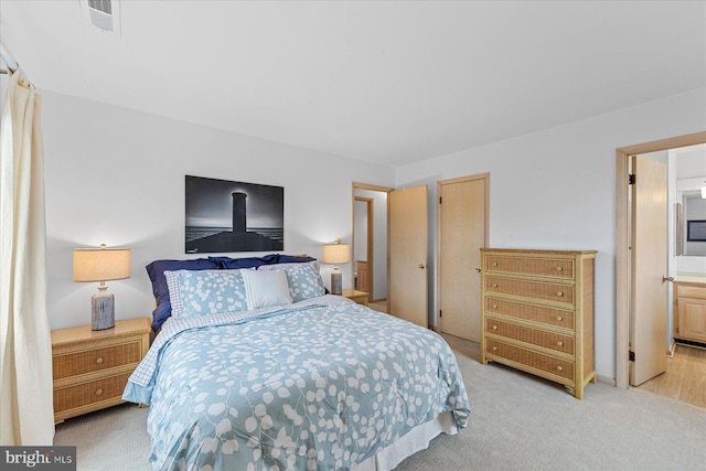 bedroom featuring ensuite bathroom and light colored carpet