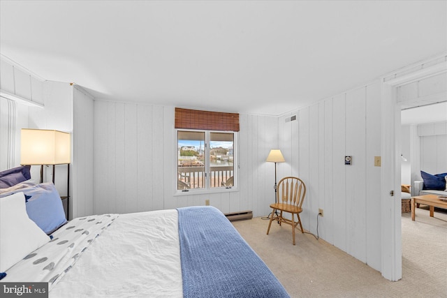 bedroom featuring baseboard heating, light carpet, and wooden walls