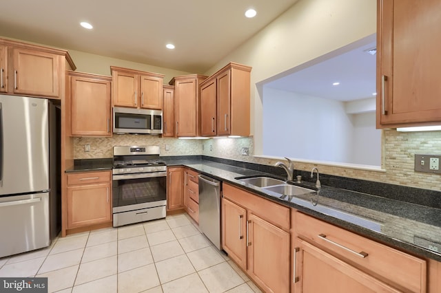 kitchen featuring sink, stainless steel appliances, dark stone countertops, decorative backsplash, and light tile patterned floors