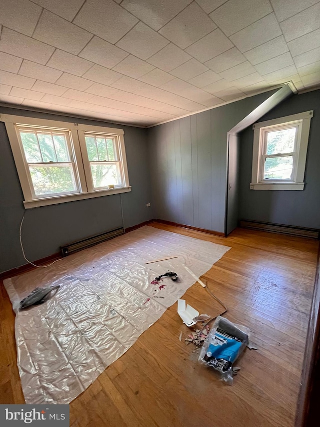 empty room featuring a healthy amount of sunlight, a baseboard radiator, and light hardwood / wood-style floors