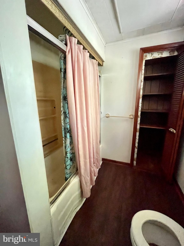 bathroom featuring hardwood / wood-style floors, toilet, and shower / bathtub combination with curtain