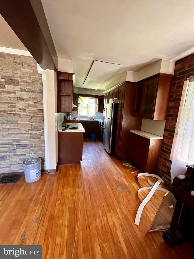 kitchen with stainless steel fridge, kitchen peninsula, and light hardwood / wood-style flooring