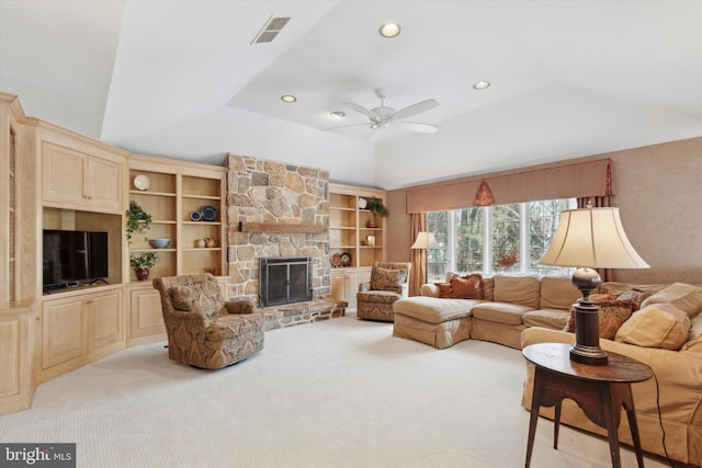 carpeted living room with ceiling fan, a stone fireplace, lofted ceiling, and built in shelves