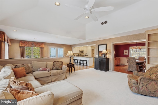 living room with ceiling fan with notable chandelier and vaulted ceiling