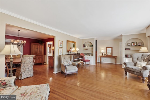 living room with an inviting chandelier, built in features, crown molding, and wood-type flooring