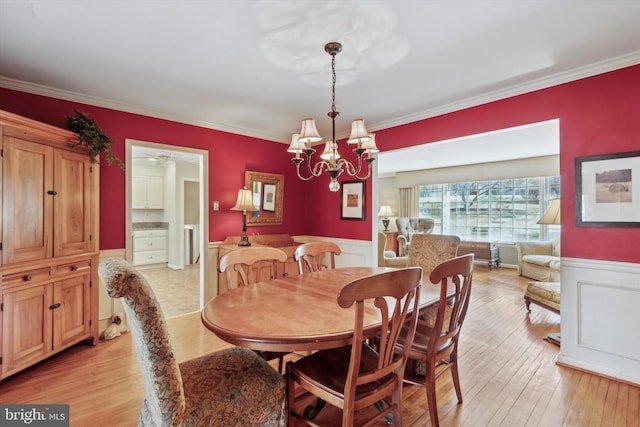 dining space with an inviting chandelier, light hardwood / wood-style floors, and crown molding