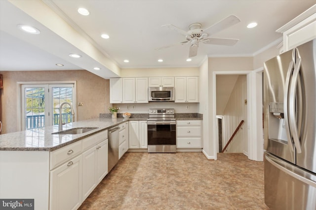 kitchen with kitchen peninsula, stone countertops, white cabinetry, appliances with stainless steel finishes, and sink