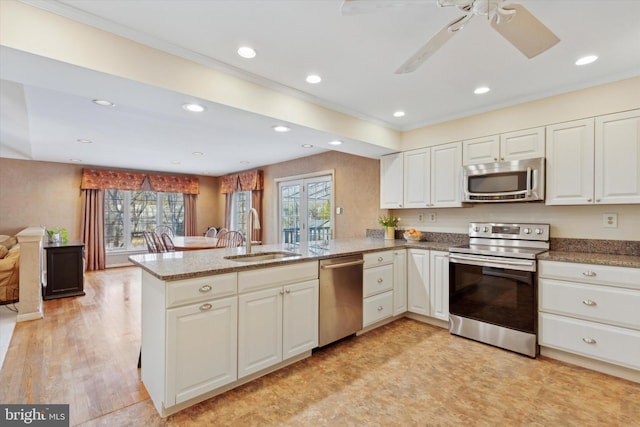 kitchen with sink, stainless steel appliances, white cabinets, and kitchen peninsula