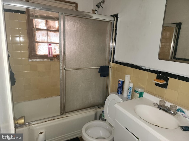 full bathroom with tasteful backsplash, bath / shower combo with glass door, vanity, tile walls, and toilet