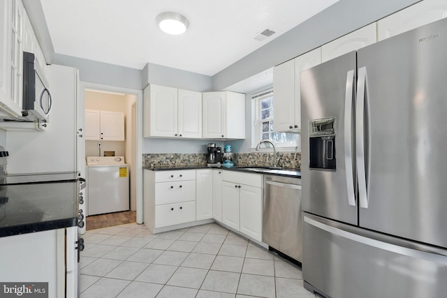 kitchen featuring stainless steel appliances, sink, white cabinets, and washer / clothes dryer