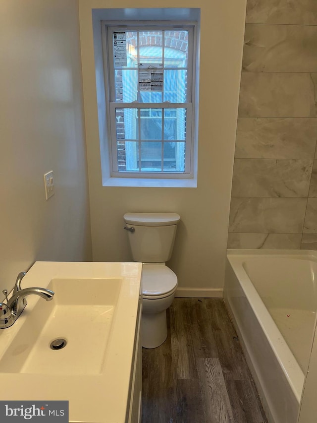 bathroom with a bathing tub, sink, wood-type flooring, and toilet