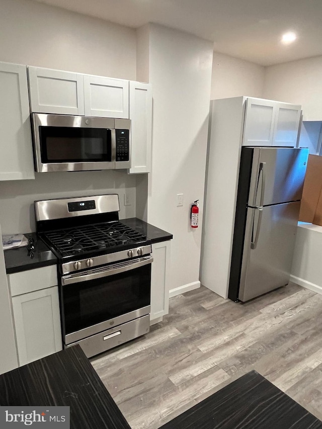 kitchen with white cabinets, appliances with stainless steel finishes, and light wood-type flooring