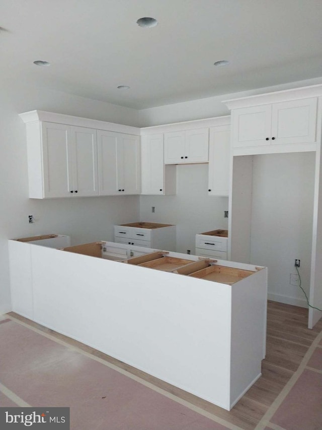 kitchen with light hardwood / wood-style floors, a center island, and white cabinetry