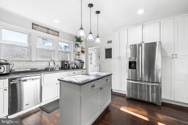 kitchen with stainless steel appliances, a kitchen island, dark wood-type flooring, white cabinetry, and hanging light fixtures