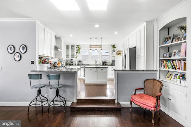 kitchen with stainless steel refrigerator, white cabinetry, dark wood-type flooring, dark stone counters, and pendant lighting