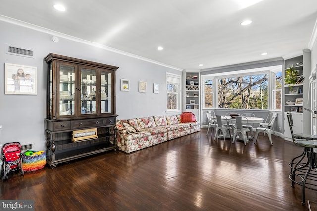 living room featuring dark hardwood / wood-style floors, built in features, and ornamental molding