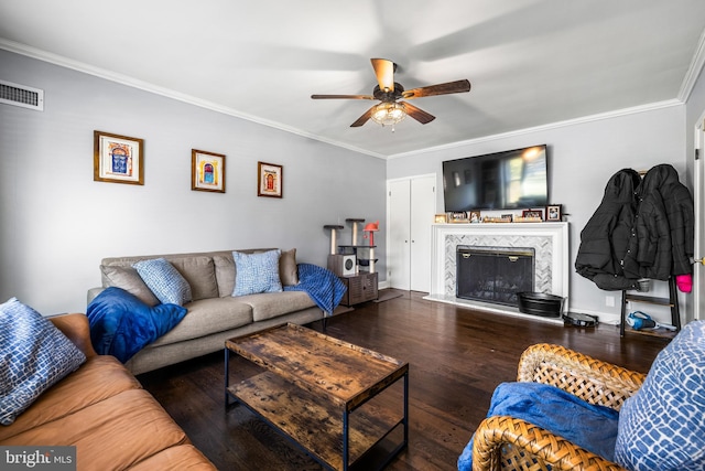 living room with ornamental molding, ceiling fan, dark wood-type flooring, and a premium fireplace