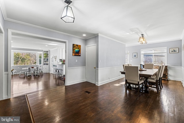 dining area with crown molding and dark wood-type flooring