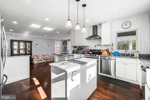 kitchen featuring white cabinets, a center island, wall chimney range hood, and stainless steel appliances