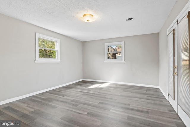 unfurnished room featuring wood-type flooring and a textured ceiling