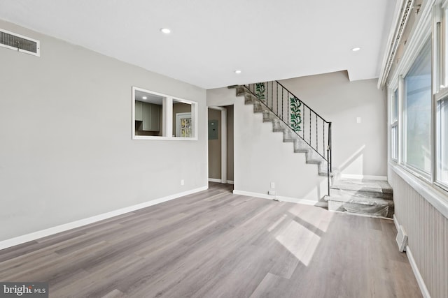 unfurnished living room with electric panel and hardwood / wood-style floors