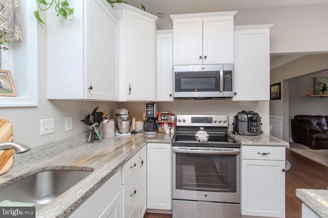 kitchen featuring sink, stainless steel appliances, light stone counters, crown molding, and white cabinets