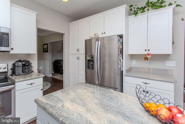 kitchen with stainless steel appliances, white cabinetry, dark hardwood / wood-style floors, and light stone counters