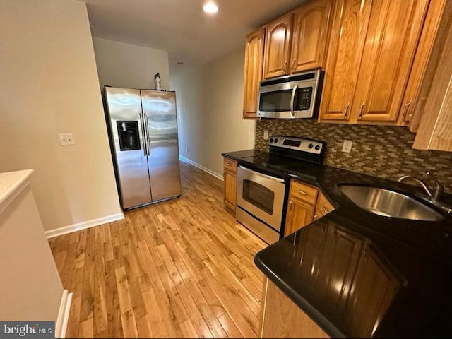 kitchen featuring backsplash, light wood-type flooring, sink, and appliances with stainless steel finishes