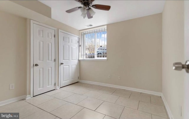 unfurnished bedroom featuring multiple closets, ceiling fan, and light tile patterned flooring