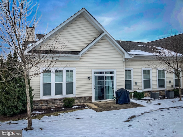 snow covered house featuring central AC