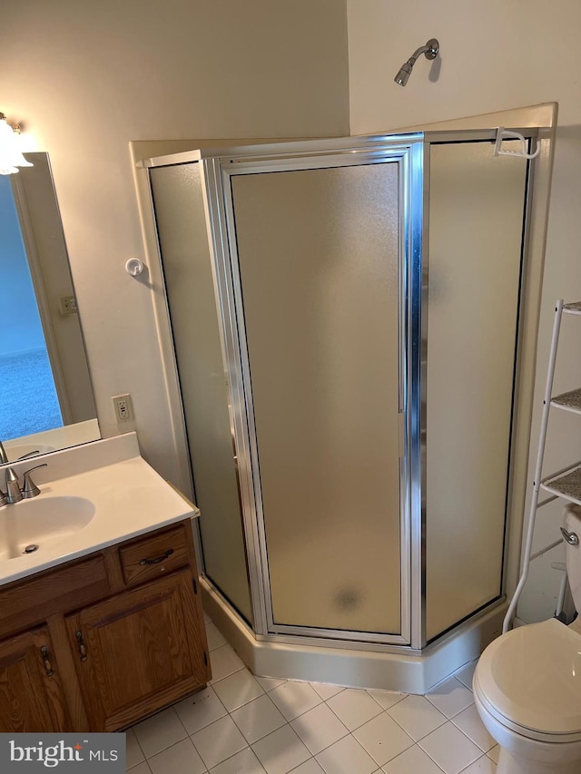 bathroom with toilet, vanity, tile patterned floors, and a shower with shower door