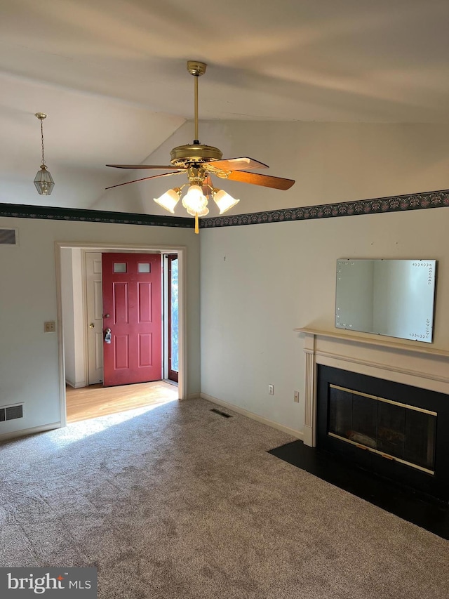 unfurnished living room with ceiling fan, carpet, and vaulted ceiling