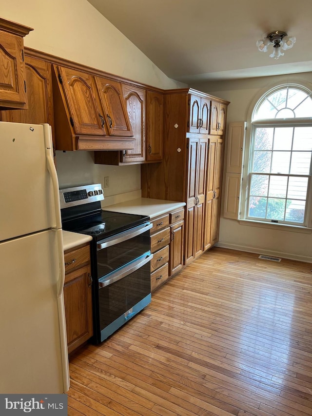 kitchen with lofted ceiling, white refrigerator, light hardwood / wood-style flooring, stainless steel electric range oven, and custom range hood