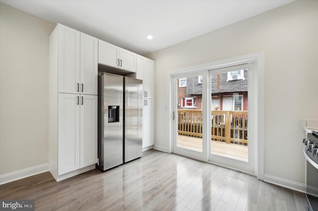 kitchen with stainless steel fridge with ice dispenser, light wood-type flooring, and white cabinetry