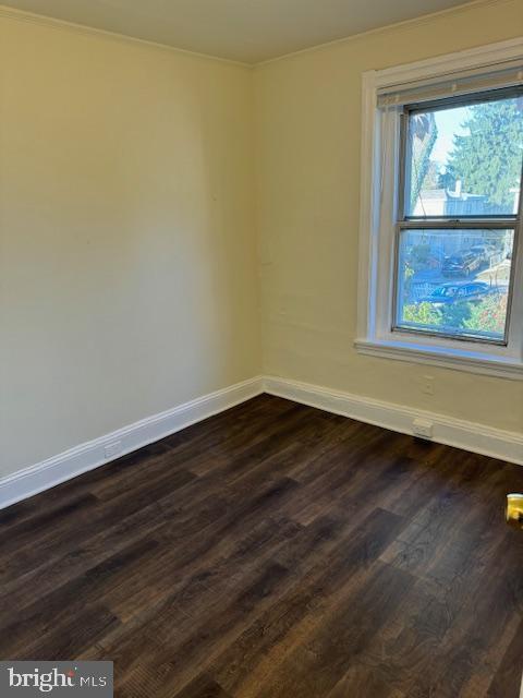 empty room featuring dark hardwood / wood-style flooring and ornamental molding