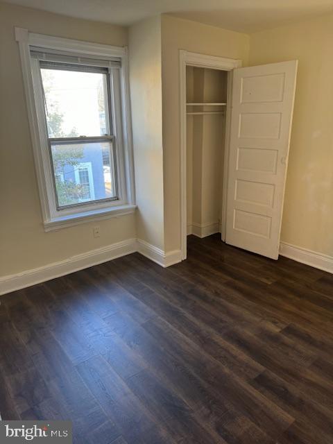 unfurnished bedroom featuring dark hardwood / wood-style floors and a closet