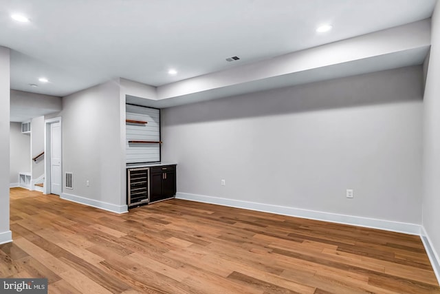 unfurnished living room with beverage cooler and light hardwood / wood-style flooring