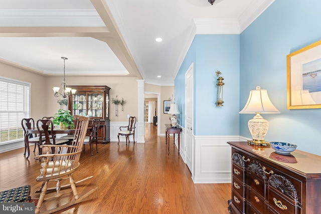 corridor with light hardwood / wood-style floors, an inviting chandelier, and crown molding