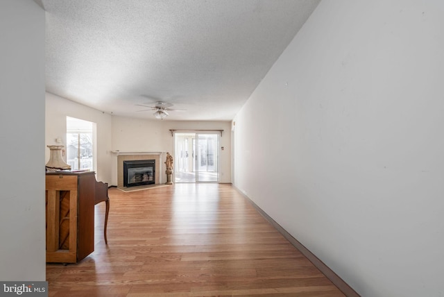 unfurnished living room with a textured ceiling, light hardwood / wood-style floors, and ceiling fan