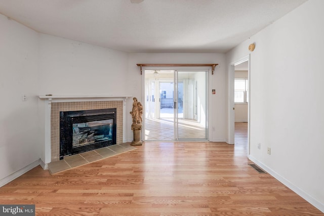 unfurnished living room with a tile fireplace and light hardwood / wood-style flooring