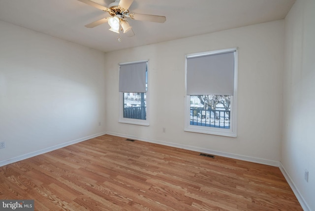 spare room featuring ceiling fan, light hardwood / wood-style floors, and a healthy amount of sunlight