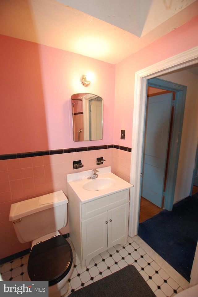 bathroom with toilet, vanity, and tile walls