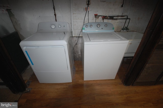 washroom with sink, washer and clothes dryer, and hardwood / wood-style floors