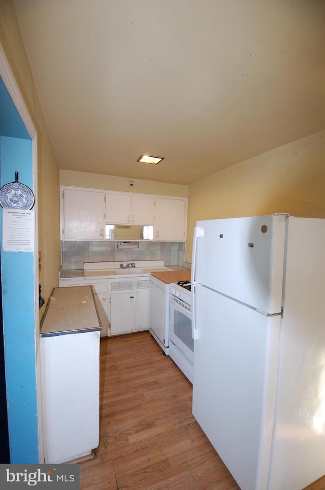 kitchen with white appliances, light wood-type flooring, decorative backsplash, sink, and white cabinetry